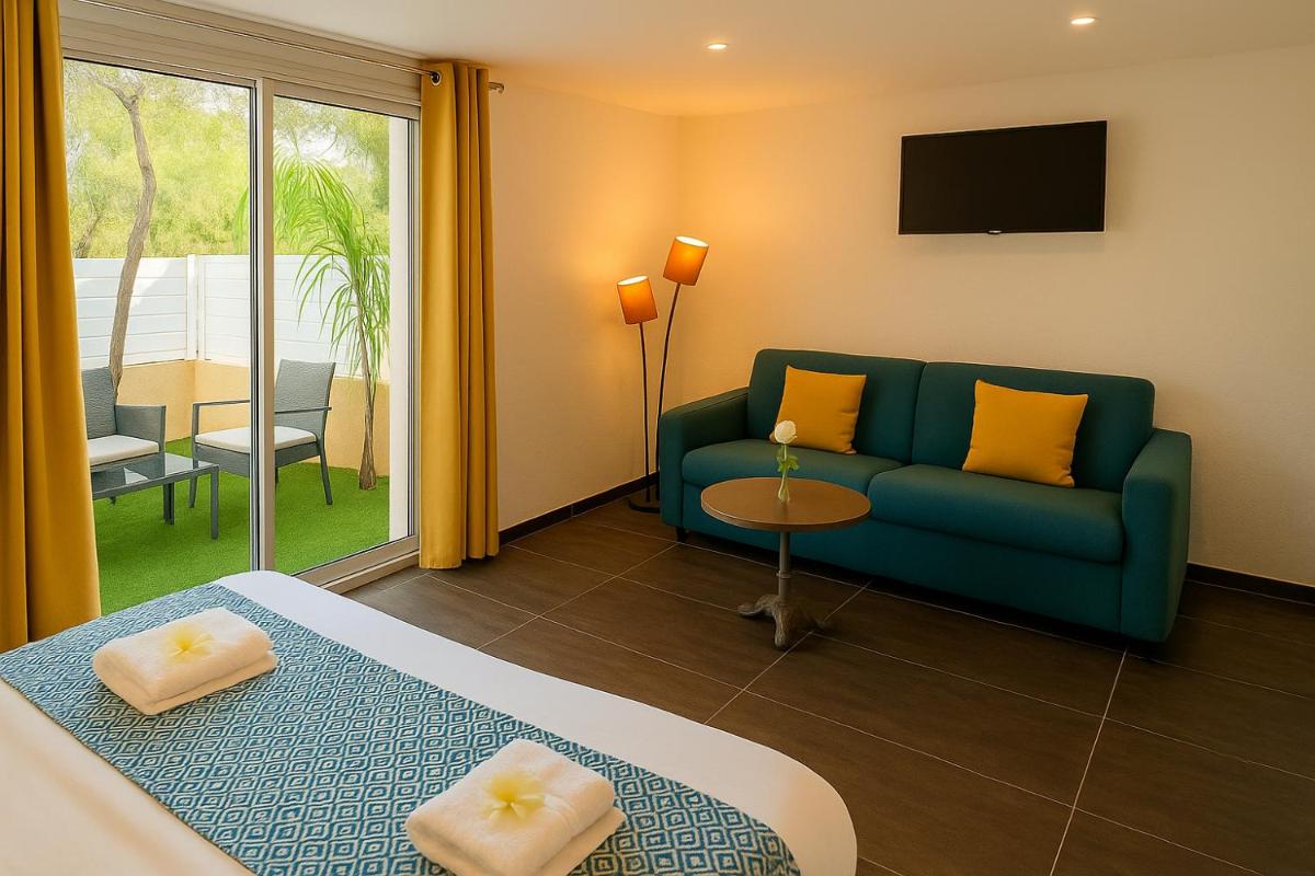 Cette chambre d'hôtel dispose d'un canapé et d'une télévision. dans l'établissement Hotel & Spa Gil de France Cap d'Agde, au Cap d'Agde 79 autres photos