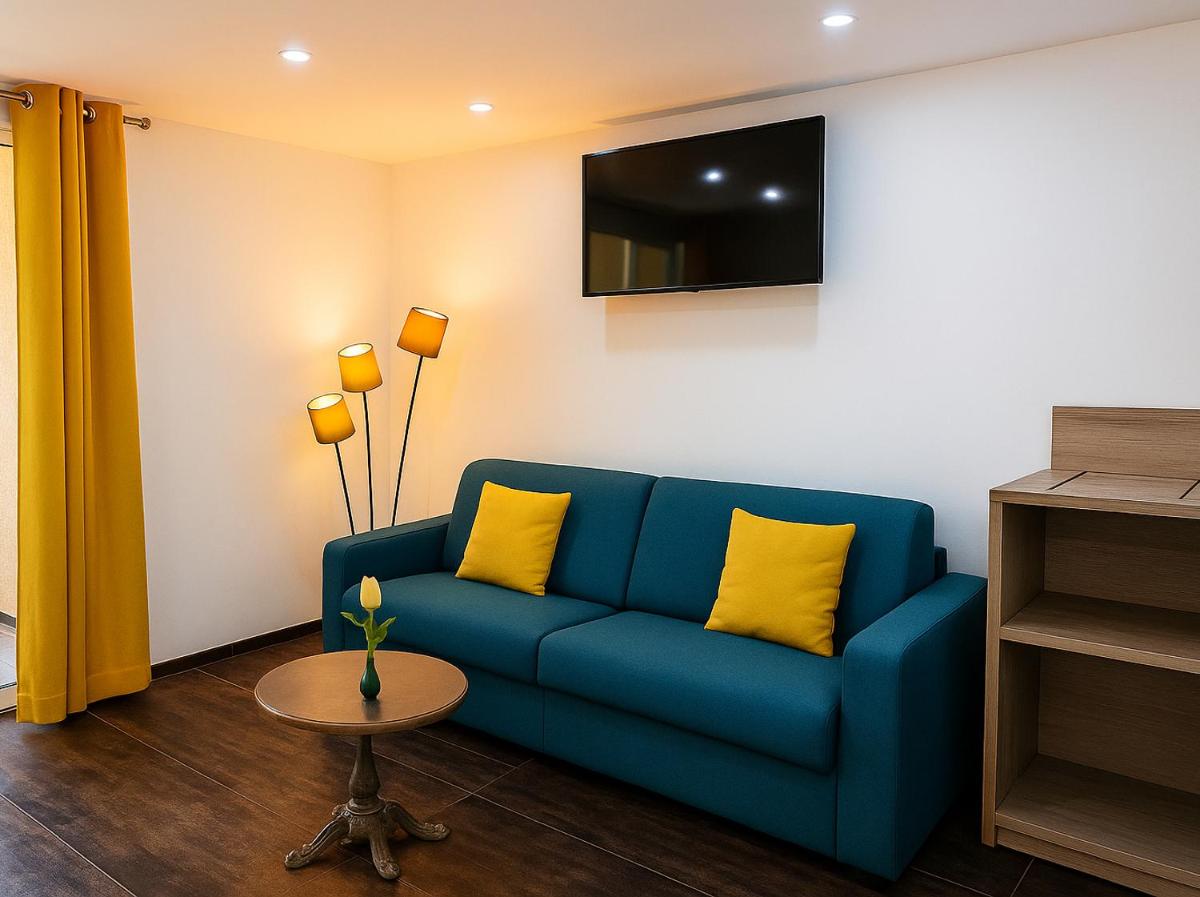 un salon avec un canapé bleu avec des coussins jaunes dans l'établissement Hotel & Spa Gil de France Cap d'Agde, au Cap d'Agde