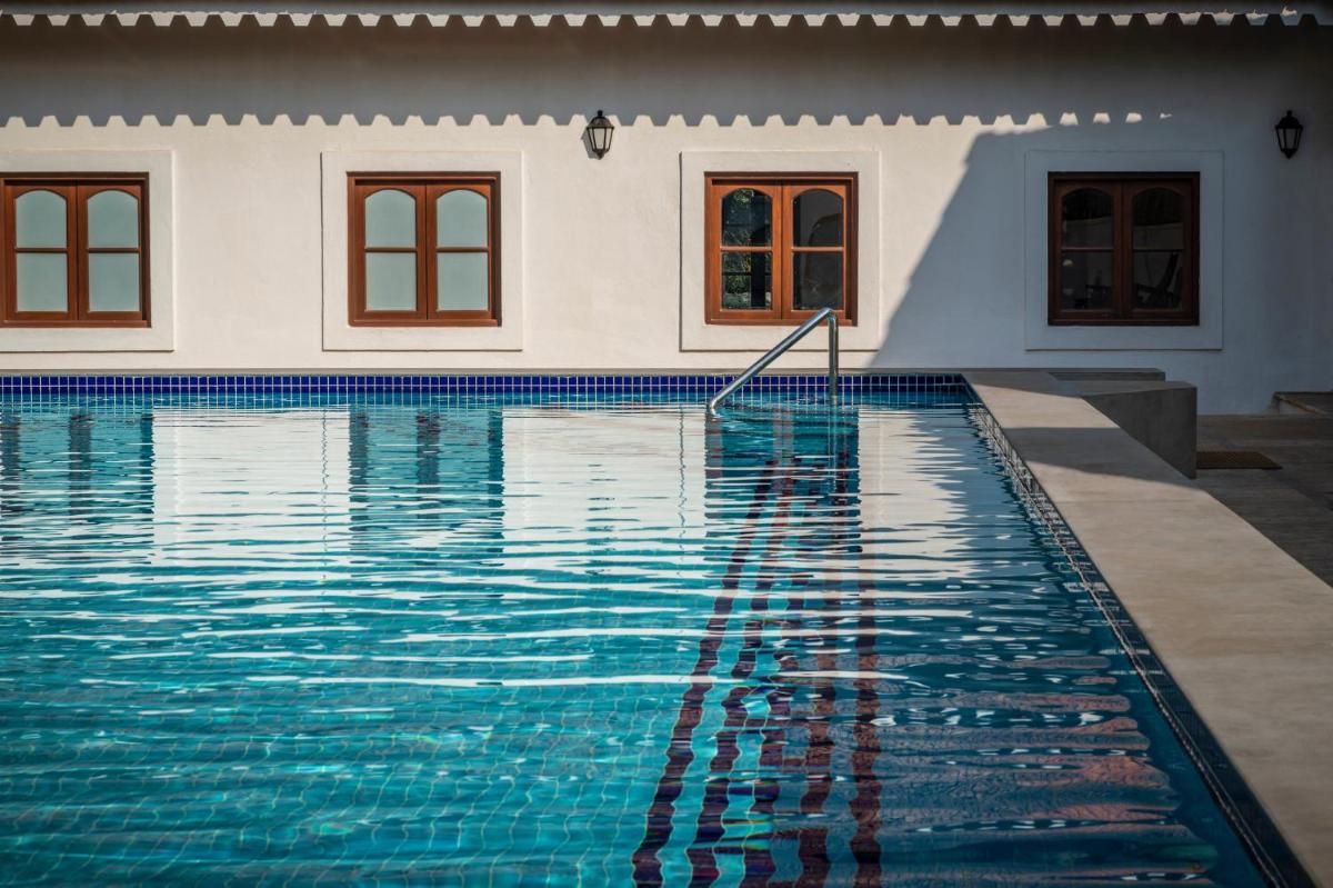a swimming pool in front of a house at The Postcard Cuelim, Goa in Cansaulim