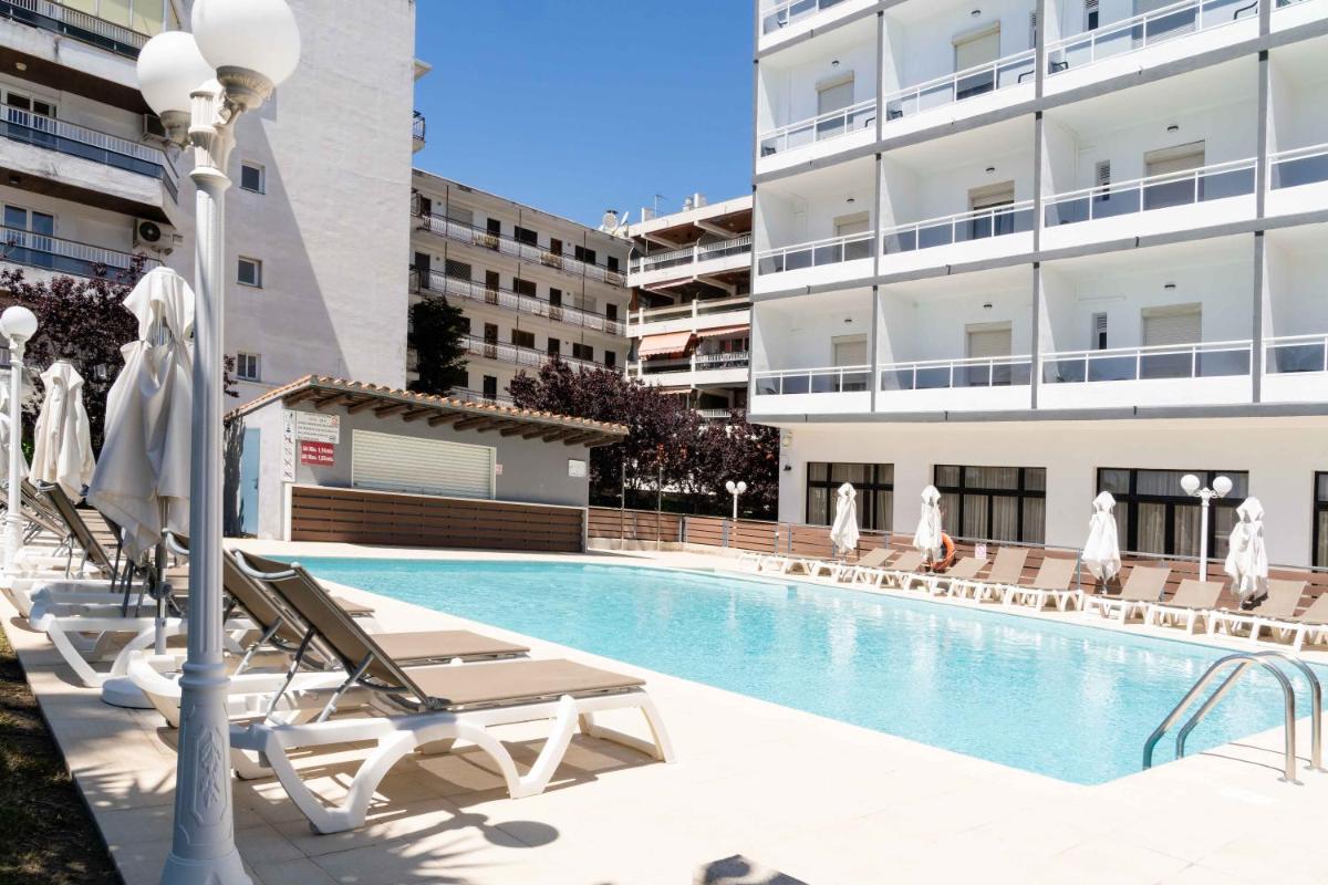 Una piscina con tumbonas y un edificio. en Hotel Planas, en Salou
