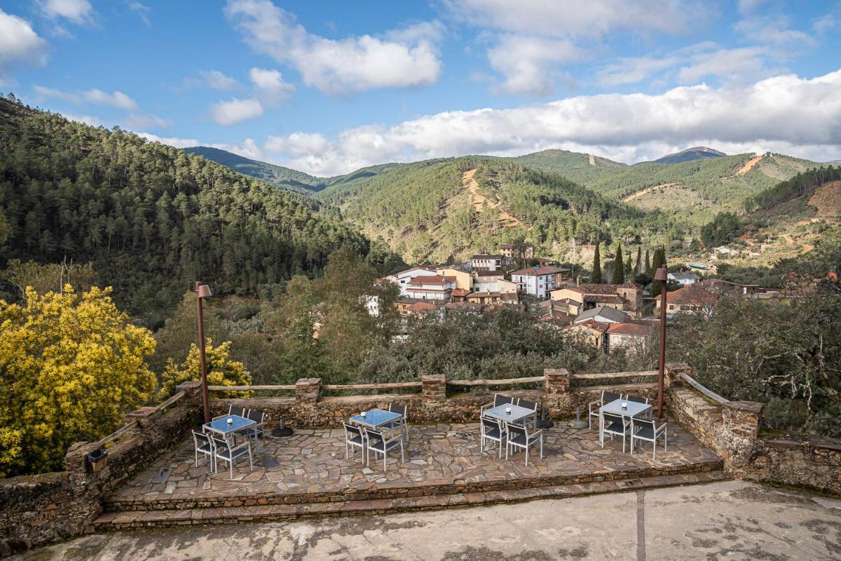 Un patio con mesas y sillas en las montañas. en Hotel Hurdes Reales, en Las Mestas