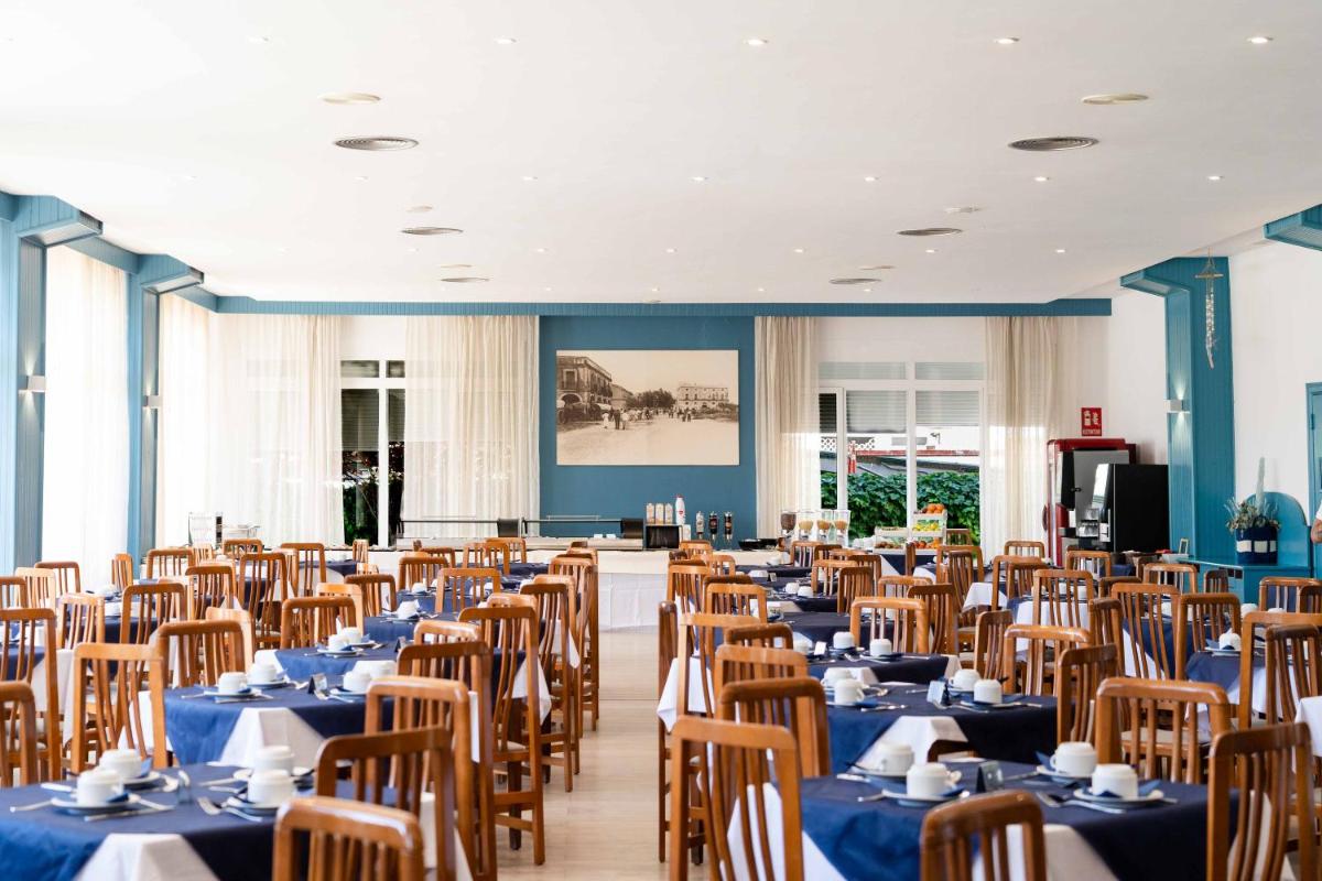 Un comedor con mesas y sillas azules. en Hotel Planas, en Salou