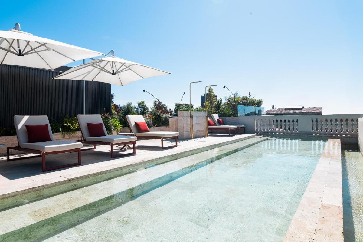 una piscina con sillas y sombrillas en la azotea en Almanac Barcelona, en Barcelona una piscina con sillas y sombrillas en la azotea en Almanac Barcelona, en Barcelona