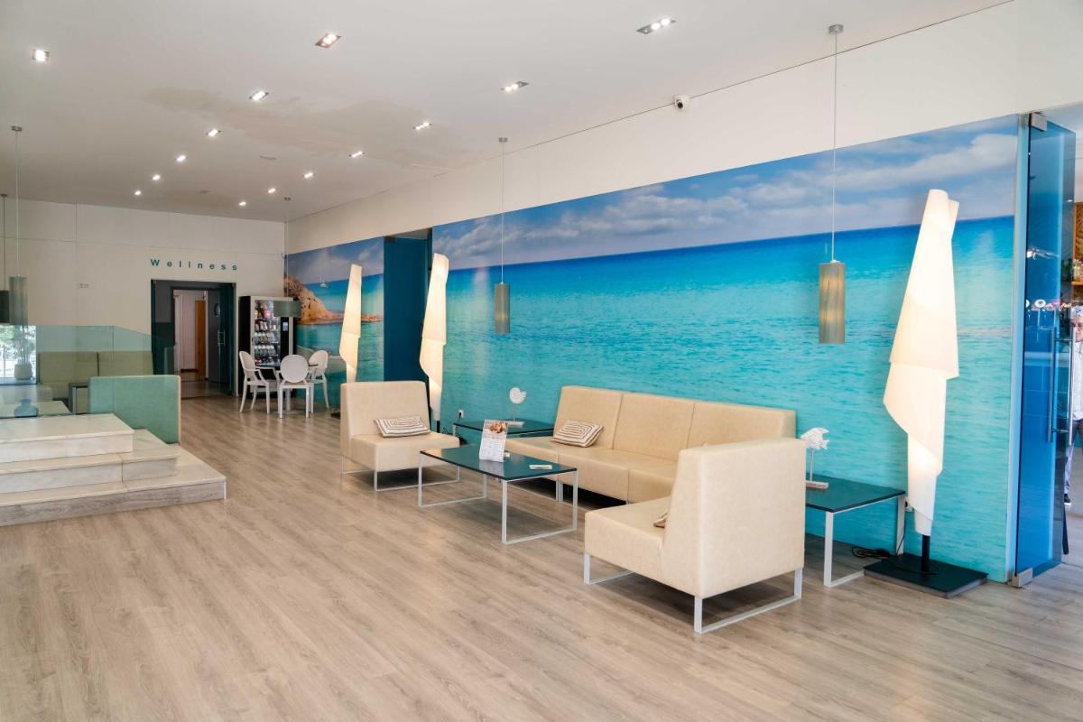 Un vestíbulo con sillas y mesas y una pintura del océano. en Hotel Planas, en Salou