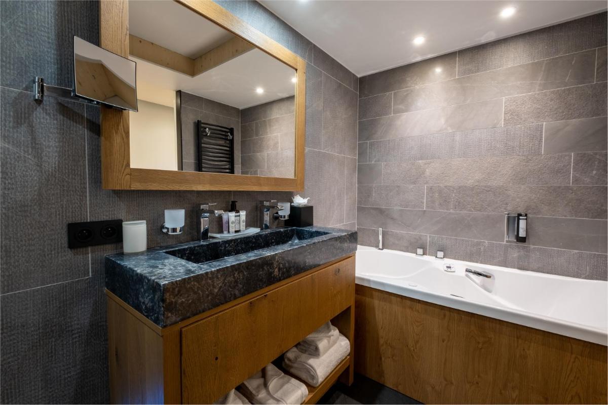 une salle de bain avec un lavabo et un grand miroir dans l'établissement Hôtel Alparena & Spa - 4 étoiles, à La Rosière
