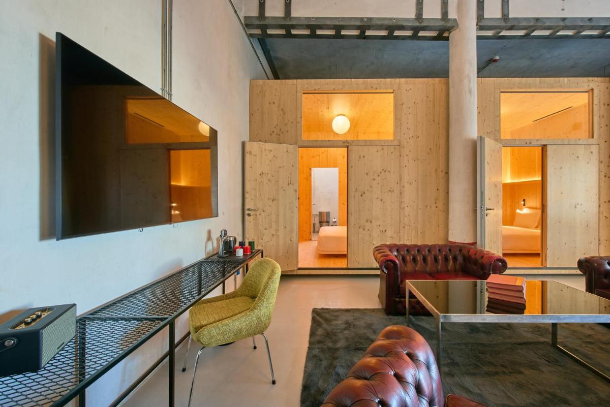 uma sala de estar com um sofá, uma mesa e cadeiras em Moagem Industrial Lodge em Viana do Alentejo