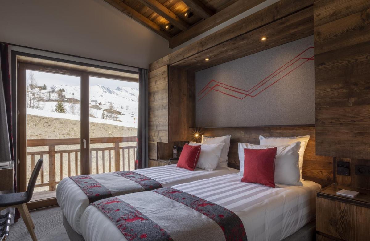 une chambre avec un grand lit avec une grande fenêtre dans l'établissement Hôtel Alparena & Spa - 4 étoiles, à La Rosière