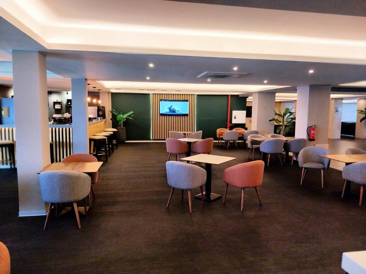 um restaurante com mesas e cadeiras e uma televisão em Hotel Navegadores em Monte Gordo