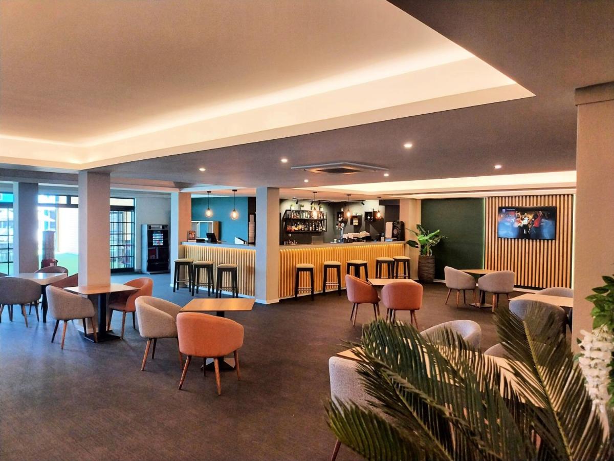 um lobby com mesas e cadeiras e um bar em Hotel Navegadores em Monte Gordo