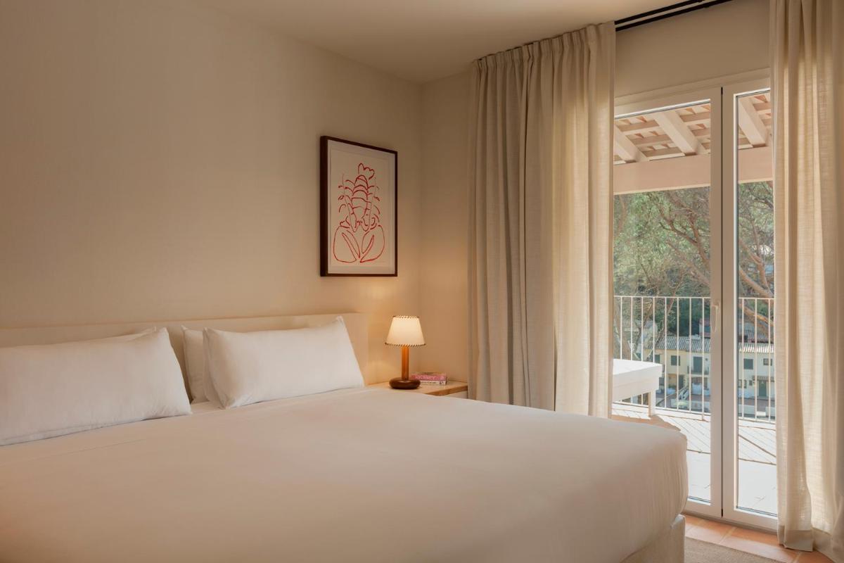 Un dormitorio con una cama blanca y una ventana grande. en Finca Victoria Hotel & Spa, en Begur