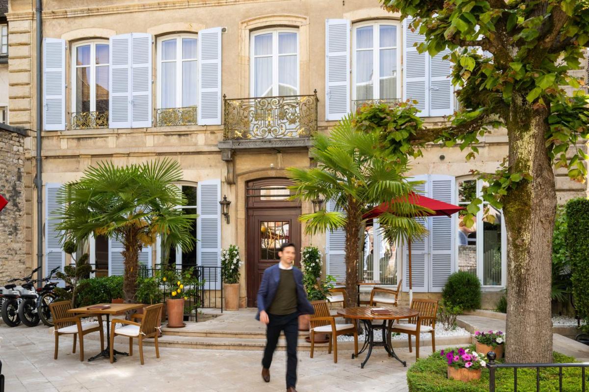 un homme en costume marchant devant un bâtiment dans l'établissement L'Hôtel, à Beaune