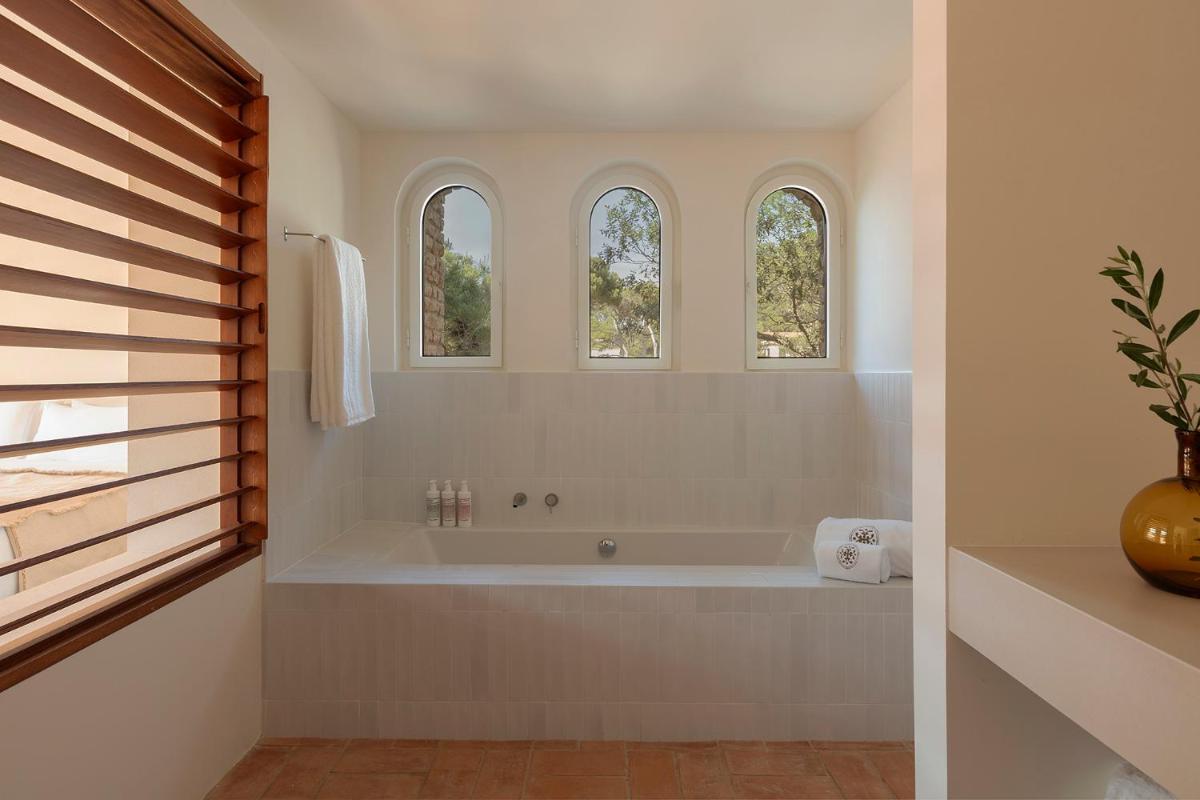 baño blanco con bañera y 3 ventanas en Finca Victoria Hotel & Spa, en Begur