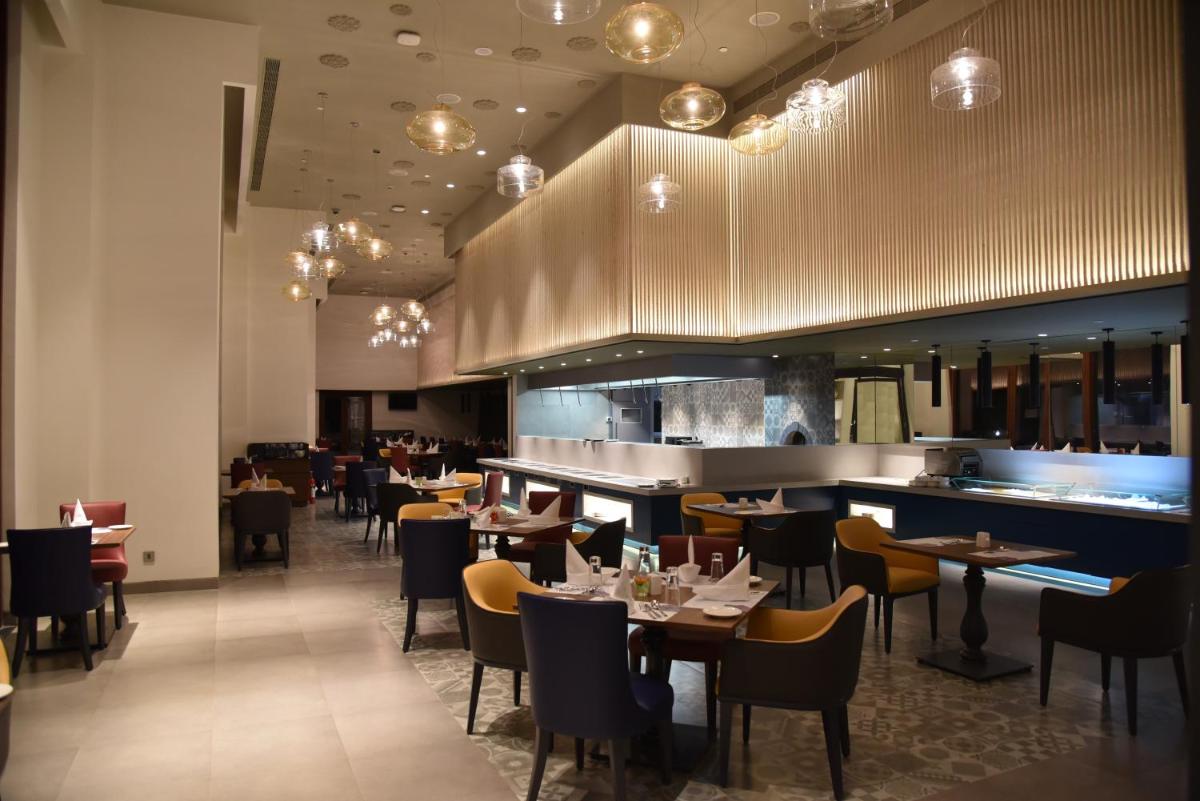 a restaurant with tables and chairs and a bar at Grand Mercure Mysore - An Accor Brand in Mysore
