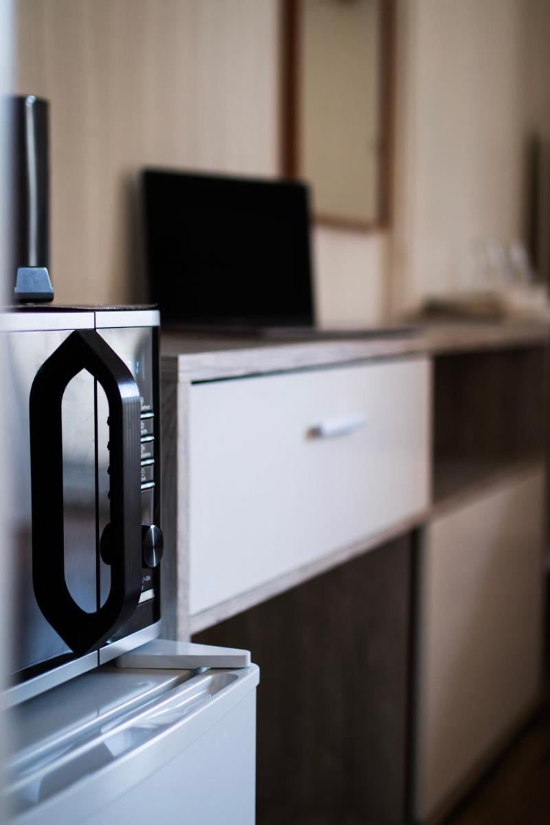 eine Mikrowelle neben einem Schreibtisch mit einem Laptop in der Unterkunft Villa ENTO HotelWestEnd in Frankfurt am Main
