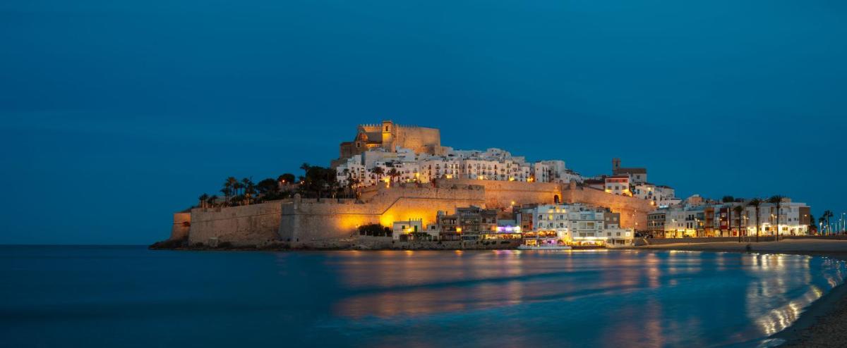 un castillo en una colina sobre el agua por la noche en Hotel RH Portocristo & Wellness, en Peñíscola