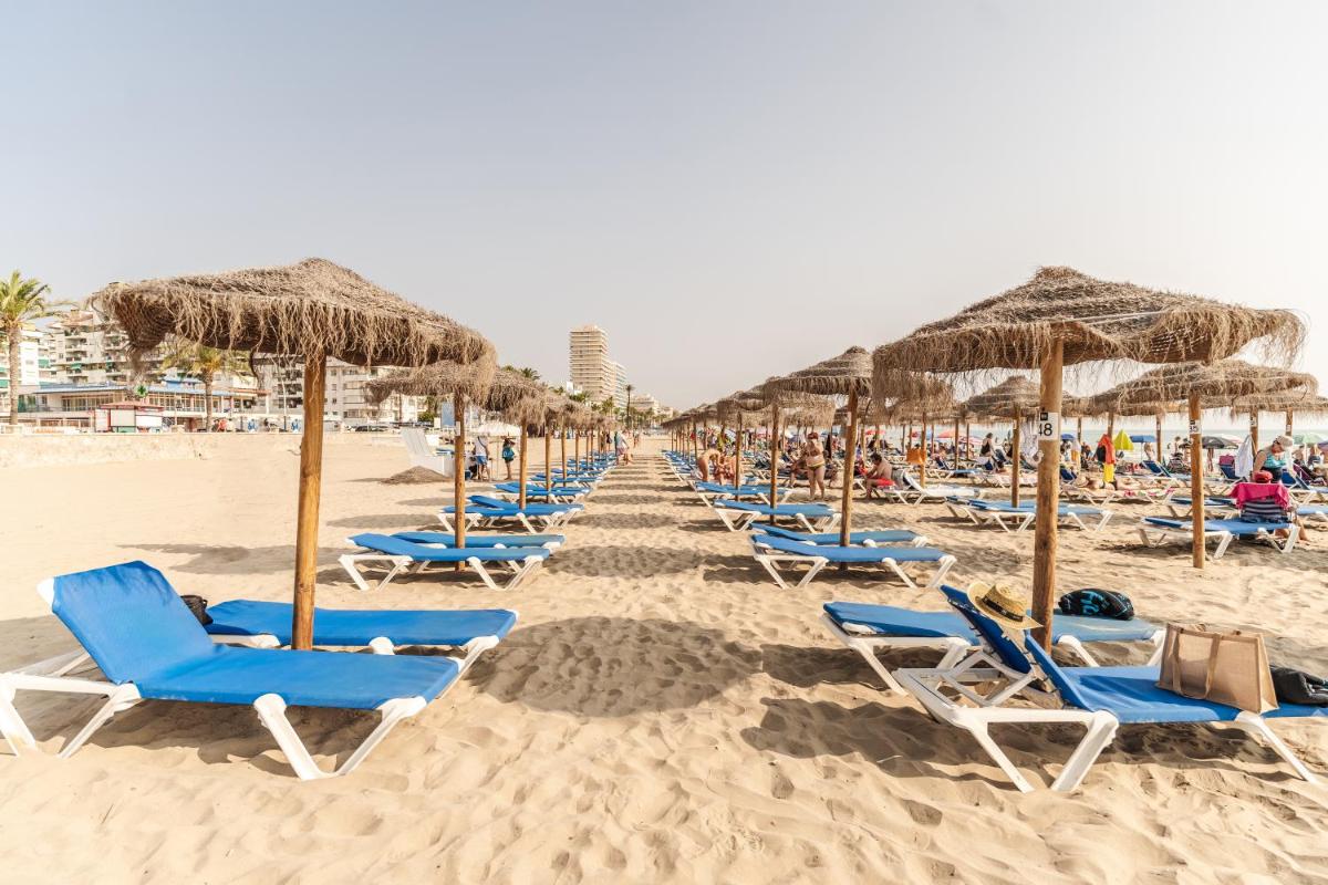 una fila de sillas y sombrillas en una playa en RH Don Carlos & Spa, en Peñíscola