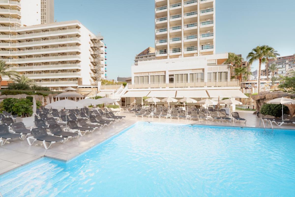una piscina con sillas, sombrillas y edificios en Hotel RH Victoria & Spa 4 Sup, en Benidorm