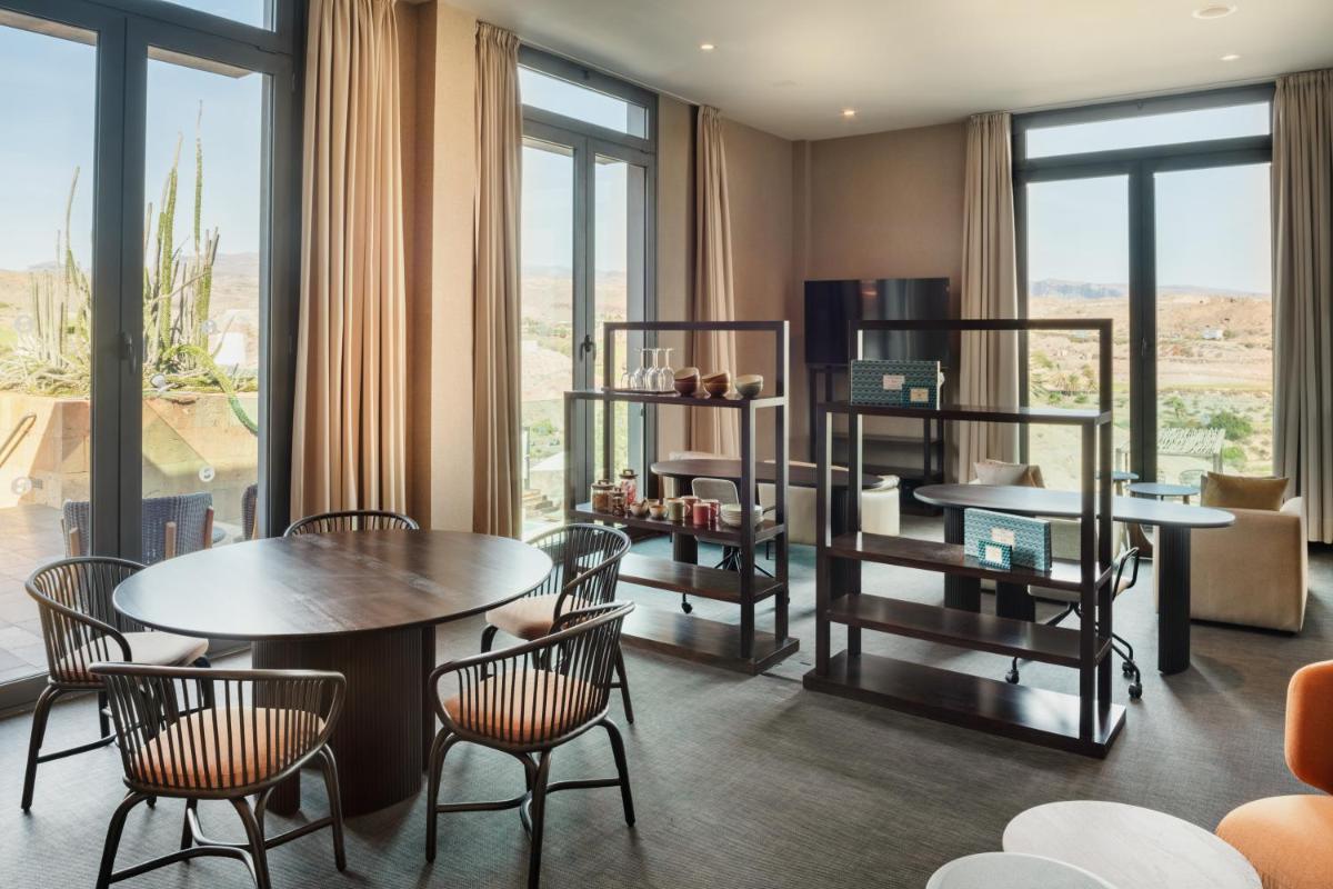 Un comedor con mesas y sillas y ventanas. en Salobre Hotel Resort & Serenity, en Salobre