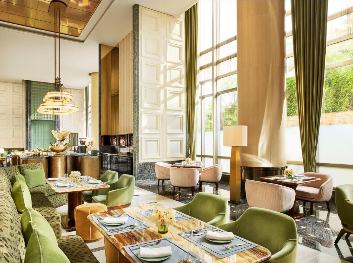 a restaurant with green chairs and tables and windows at Four Seasons Hotel Mumbai in Mumbai