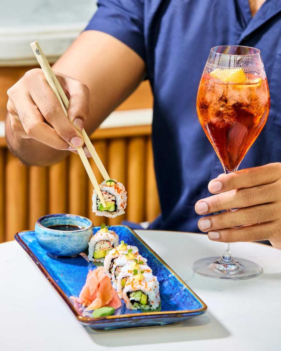 a person sitting at a table with sushi and a drink at Four Seasons Hotel Mumbai in Mumbai