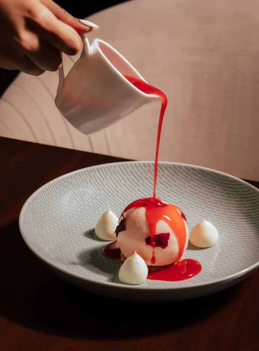 a person pouring sauce on a dessert on a plate at Four Seasons Hotel Mumbai in Mumbai