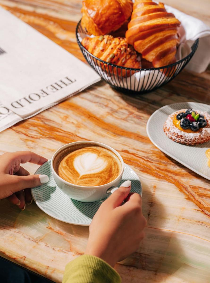 a table with a cup of coffee and a plate of pastries at Four Seasons Hotel Mumbai in Mumbai