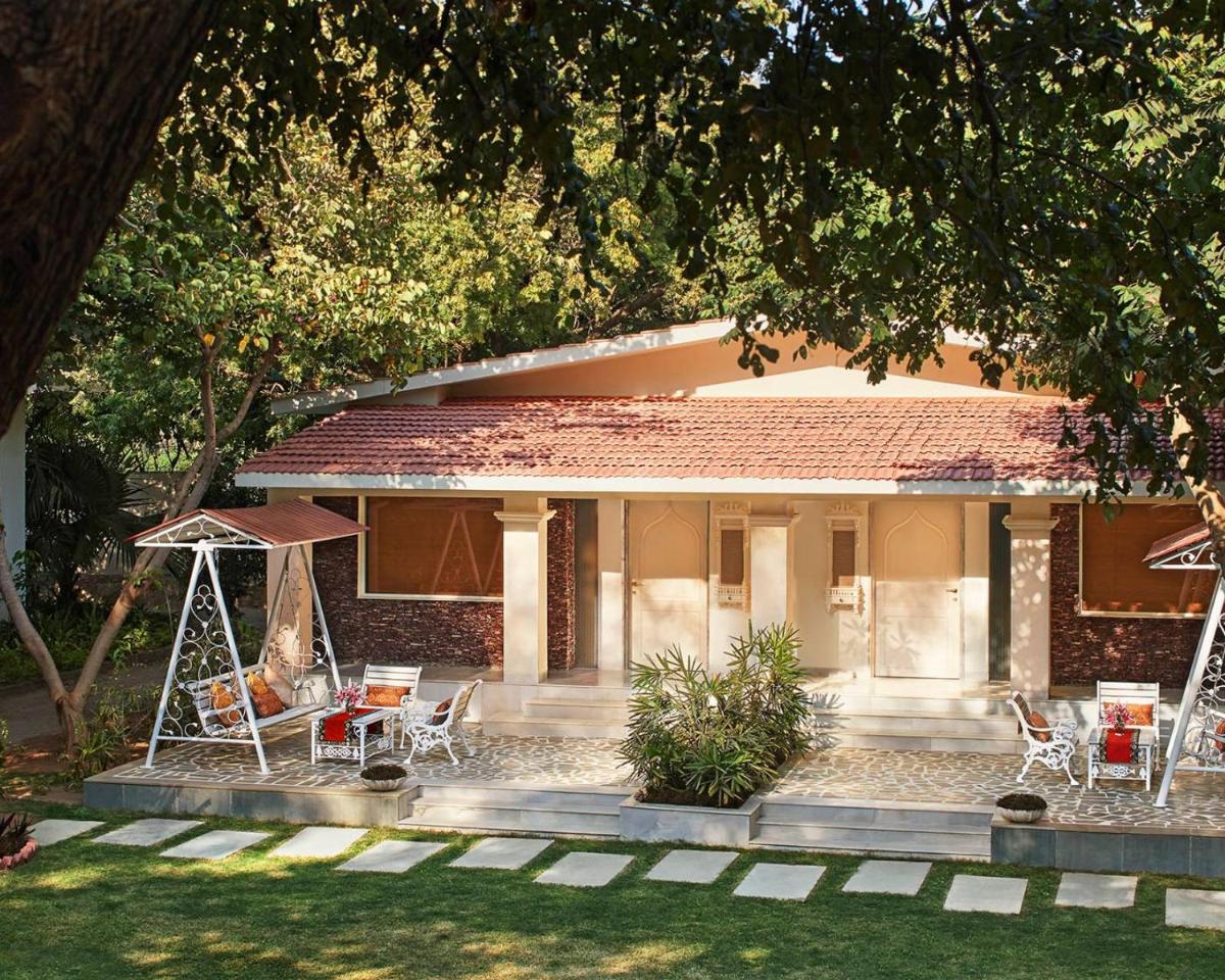 a house with chairs and a swing in the yard at Taj Aravali Resort & Spa Udaipur in Udaipur