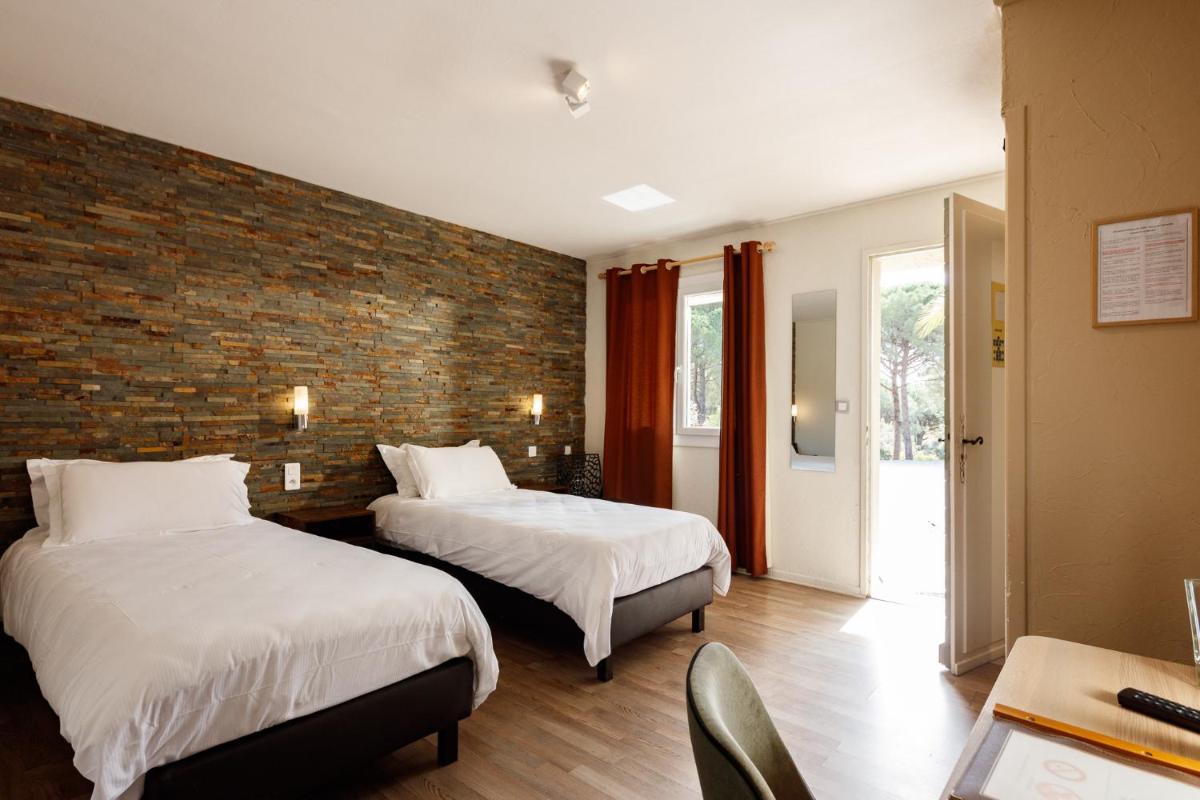 une chambre d'hôtel avec deux lits et un mur de briques dans l'établissement Auberge Val Moureze Hôtel & Spa, à Mourèze 112 autres photos