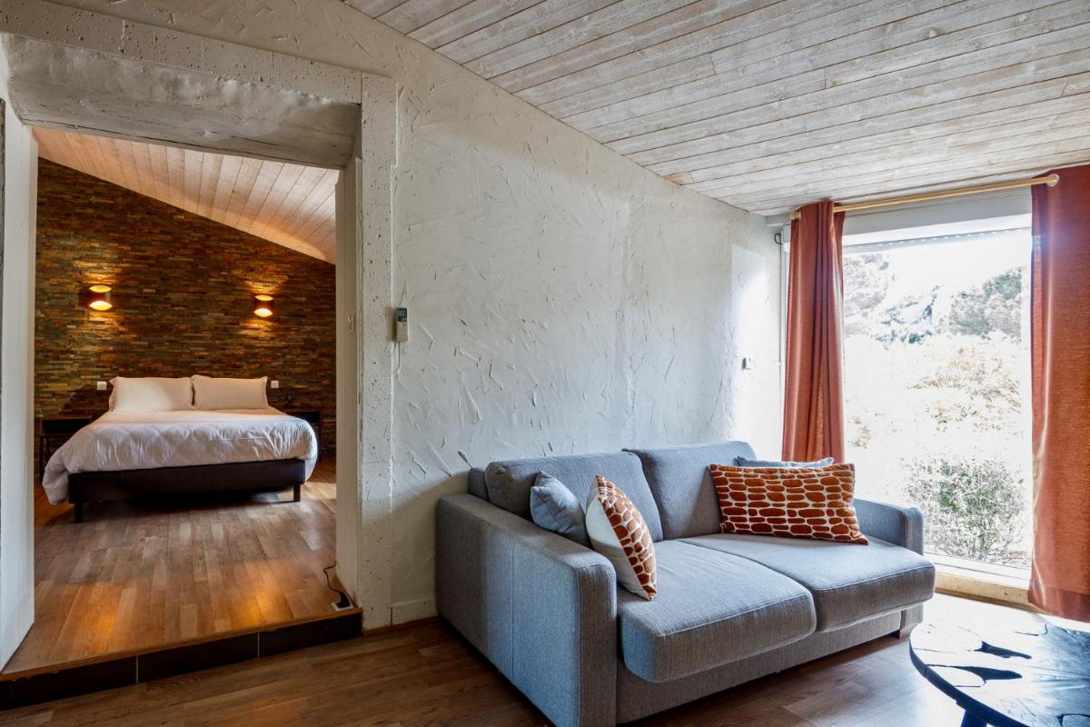 un salon avec un canapé et un lit dans l'établissement Auberge Val Moureze Hôtel & Spa, à Mourèze