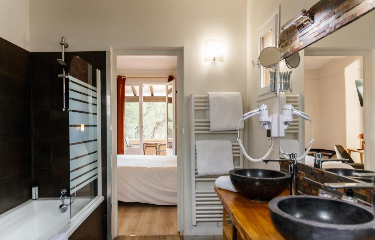 une salle de bains avec deux lavabos et une chambre dans l'établissement Auberge Val Moureze Hôtel & Spa, à Mourèze