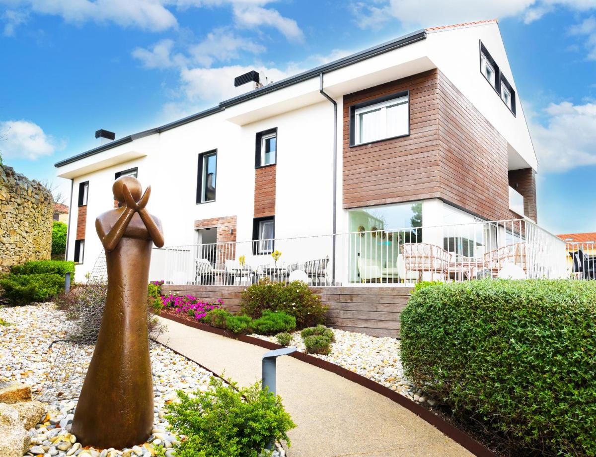 una casa con una estatua delante de ella en Hotel Spa Meiga do Mar, en Carnota