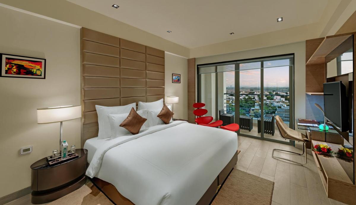 a bedroom with a large white bed and a large window at Wyndham Ahmedabad Shela in Ahmedabad
