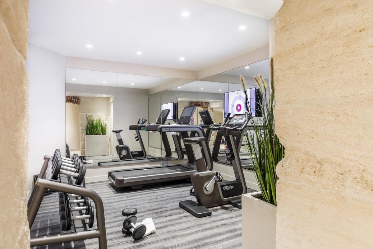 une salle de sport avec tapis de course et machines elliptiques dans l'établissement Maison Albar- Le Champs-Elysées, à Paris