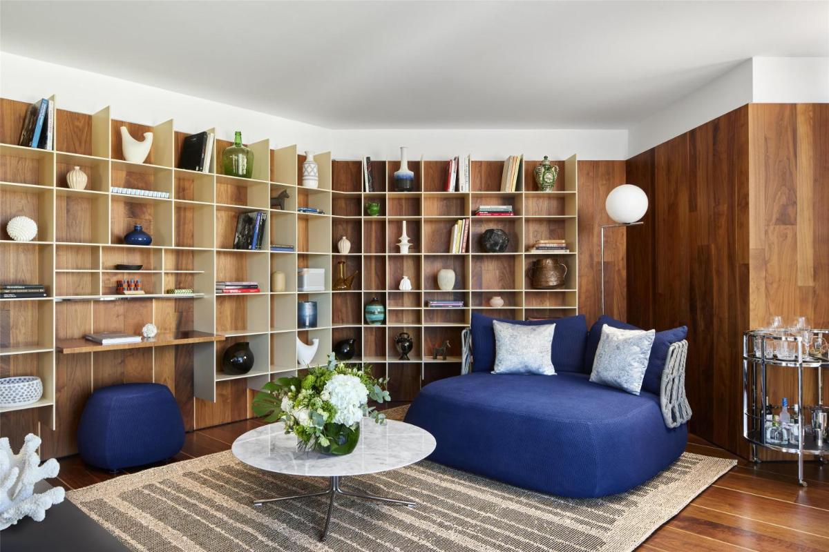 Una sala de estar con un sofá azul y un estante con jarrones. en NH Collection Ibiza, en Ibiza