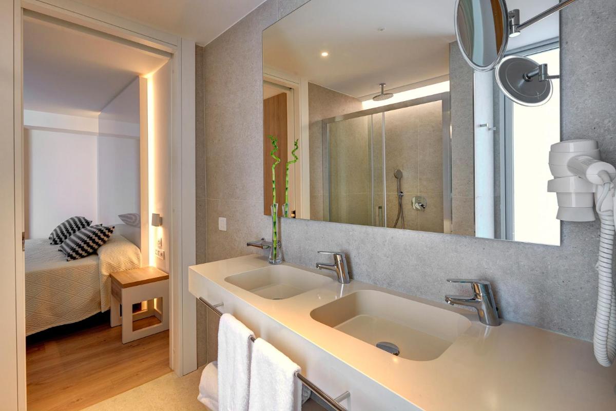 Un baño con lavabo, espejo y cama. en Hipotels Bahia Cala Millor - Adults Only, en Cala Millor