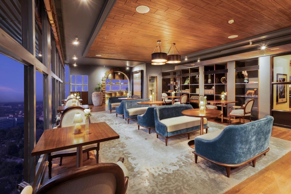 a restaurant with blue chairs and tables and windows at Le Meridien New Delhi in New Delhi a restaurant with blue chairs and tables and windows at Le Meridien New Delhi in New Delhi