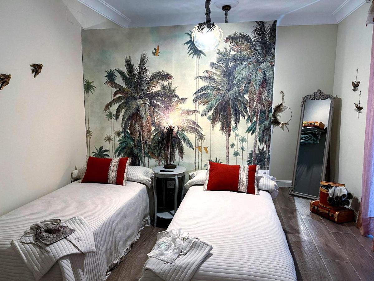 2 camas en una habitación con un mural de palmeras en Hotel Boutique iulia 5 Estrellas, en Zafra