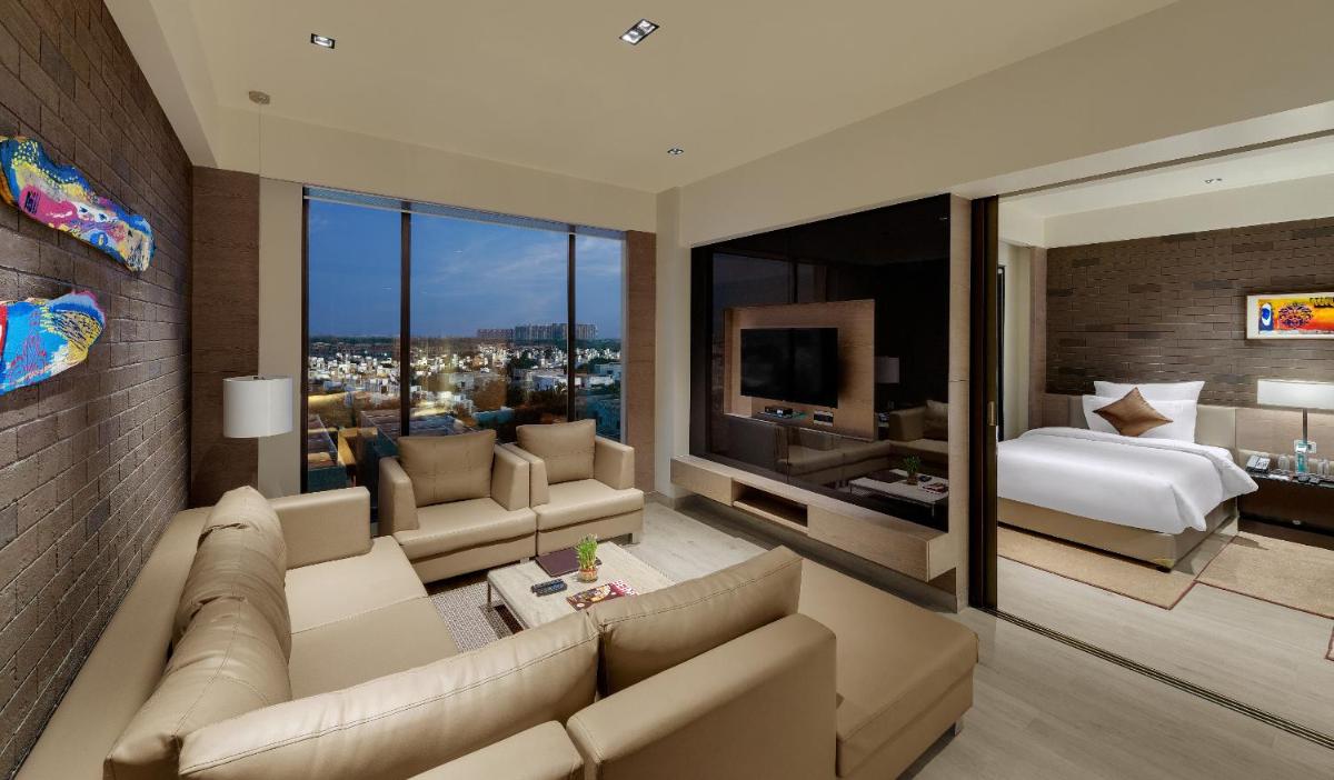 a living room with a couch and a bedroom at Wyndham Ahmedabad Shela in Ahmedabad a living room with a couch and a bedroom at Wyndham Ahmedabad Shela in Ahmedabad