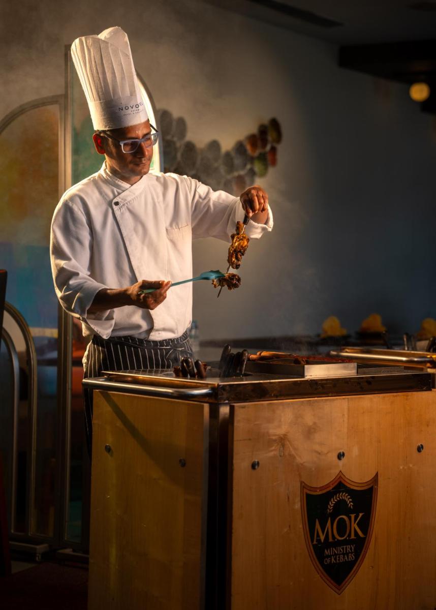 a chef preparing food on top of a stove at Novotel Kolkata Hotel and Residences in Kolkata a chef preparing food on top of a stove at Novotel Kolkata Hotel and Residences in Kolkata