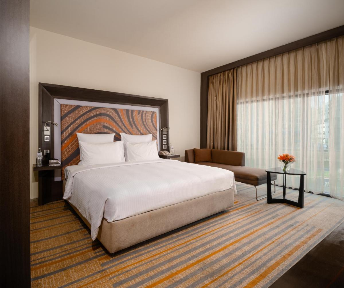 a bedroom with a large bed and a large window at Novotel Kolkata Hotel and Residences in Kolkata a bedroom with a large bed and a large window at Novotel Kolkata Hotel and Residences in Kolkata