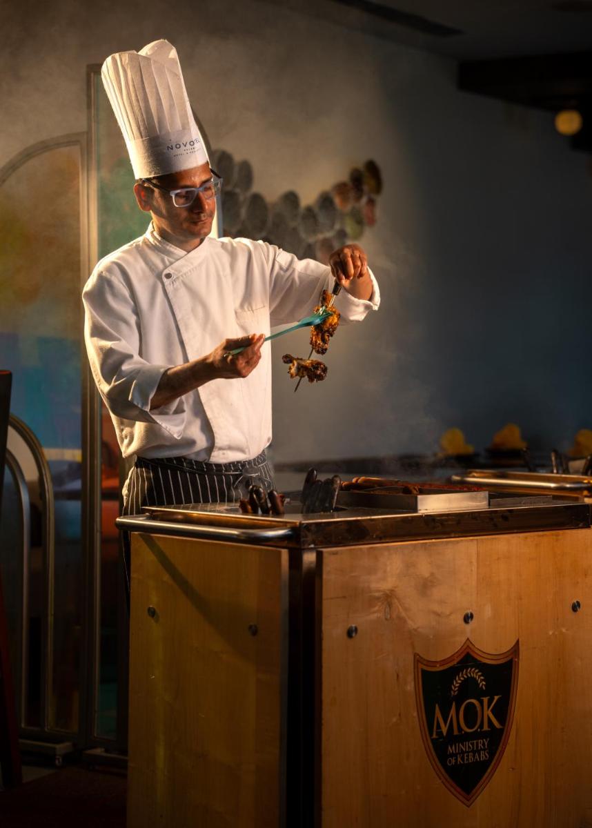 a man in a chefs hat is preparing food at Novotel Kolkata Hotel and Residences in Kolkata a man in a chefs hat is preparing food at Novotel Kolkata Hotel and Residences in Kolkata