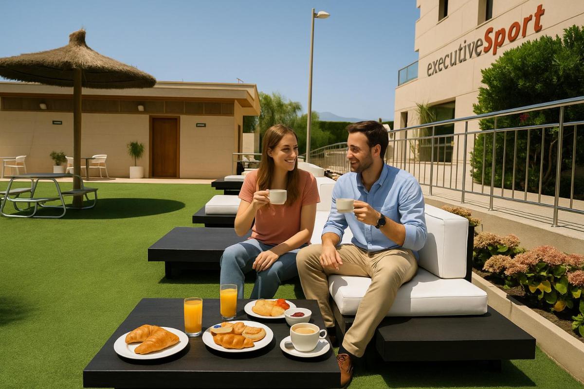 Un hombre y una mujer sentados en un patio con comida. en Executive Sport, en Totana