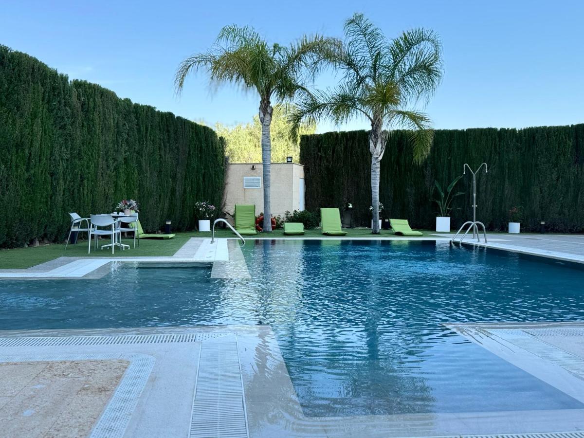 una piscina con palmeras y una mesa en Executive Sport, en Totana