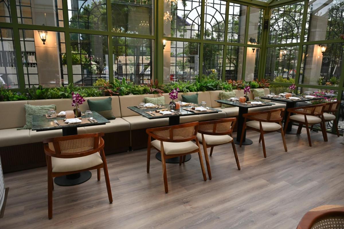 a dining room with tables and chairs in a building at Novotel Ahmedabad in Ahmedabad