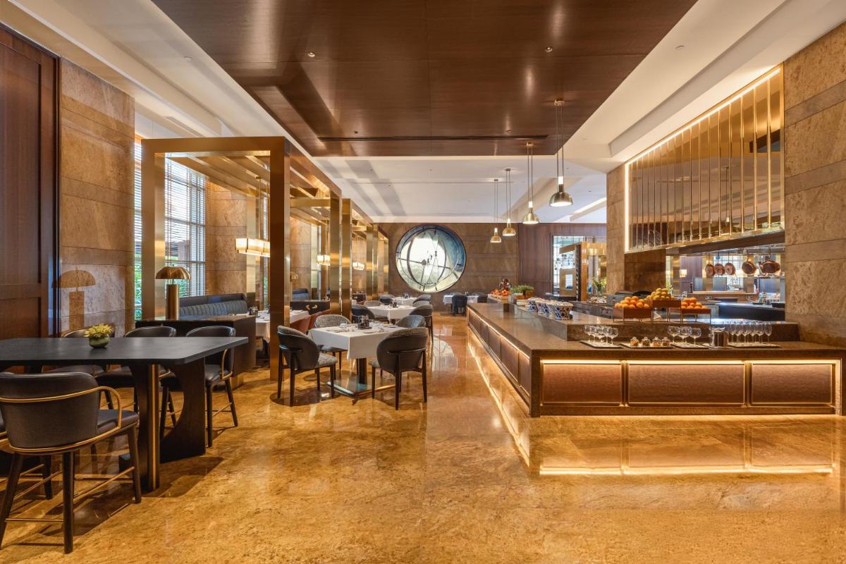 a restaurant with tables and chairs and a clock on the wall at Grand Hyatt Mumbai Hotel and Residences in Mumbai