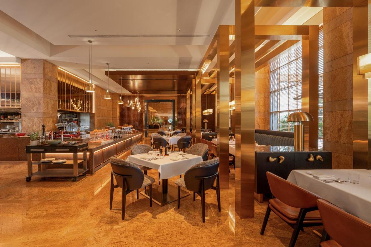 a restaurant with tables and chairs and a bar at Grand Hyatt Mumbai Hotel and Residences in Mumbai