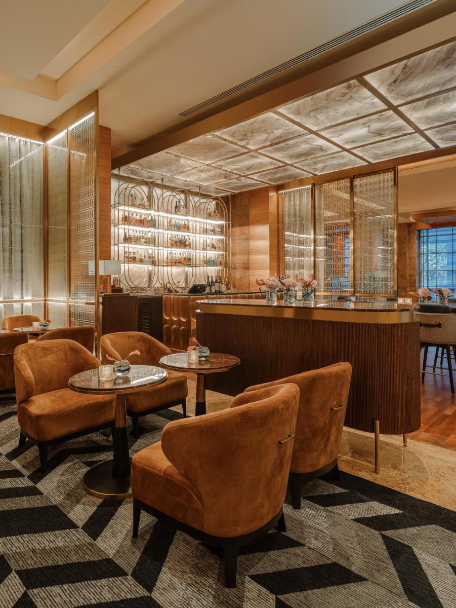 a lobby with tables and chairs and a bar at Grand Hyatt Mumbai Hotel and Residences in Mumbai