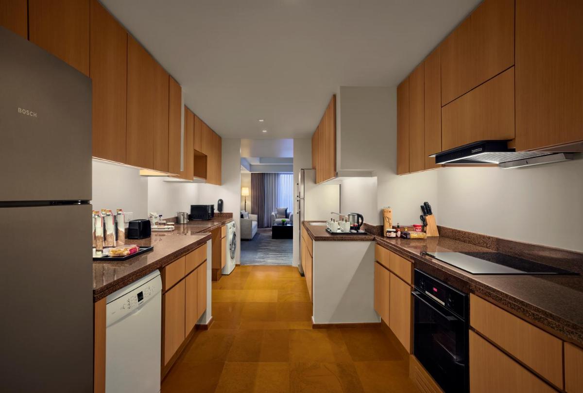 a large kitchen with wooden cabinets and white appliances at Grand Hyatt Mumbai Hotel and Residences in Mumbai