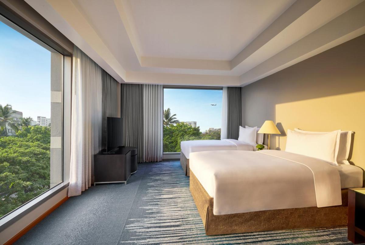 a hotel room with two beds and a large window at Grand Hyatt Mumbai Hotel and Residences in Mumbai