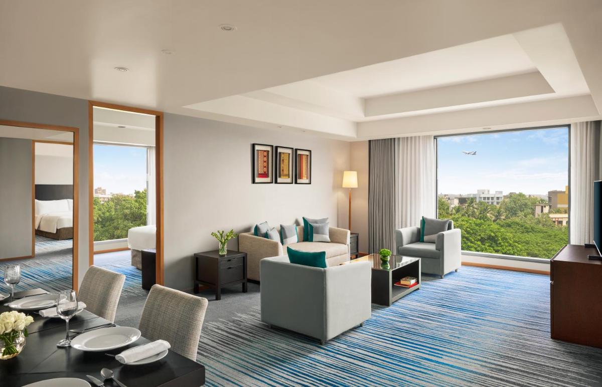 a hotel suite with a living room with a view at Grand Hyatt Mumbai Hotel and Residences in Mumbai